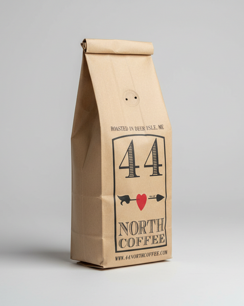 Hand holding a bag of 44 North Coffee against a blue curtain background
