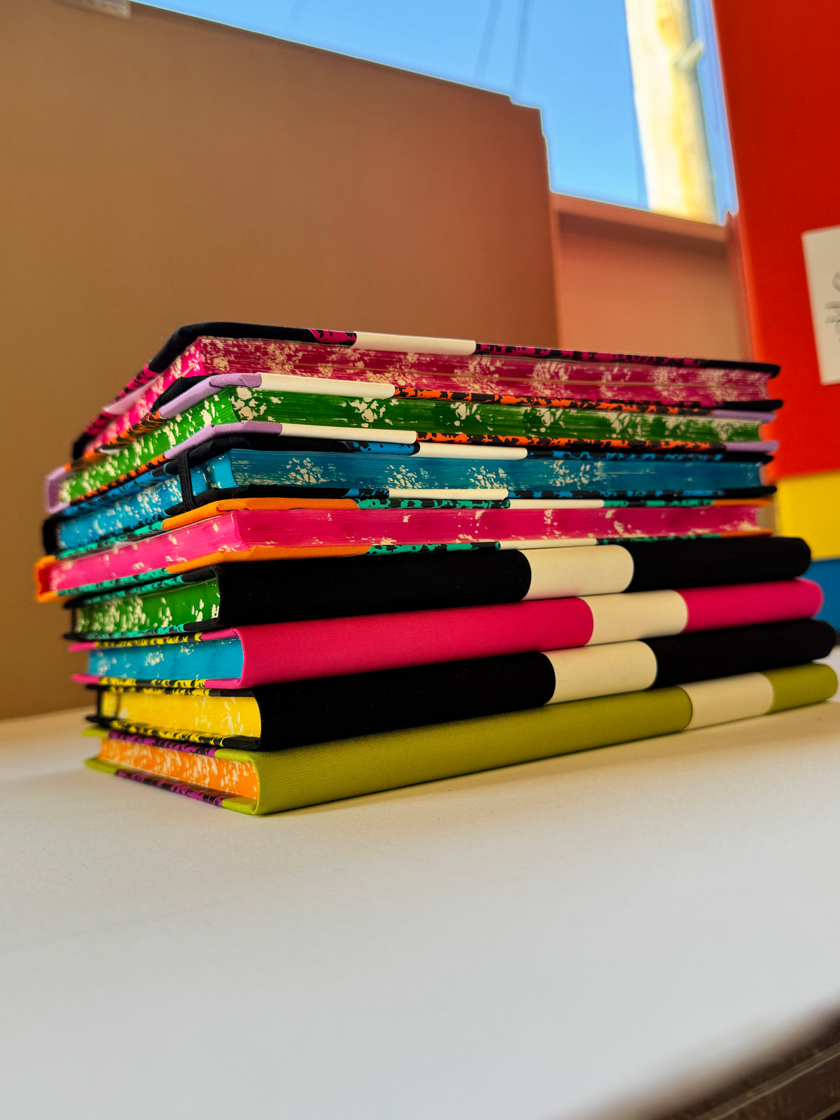 A set of colorful fabric-covered binder rings or file folders with Japanese floral patterns, displayed vertically on a shelf.