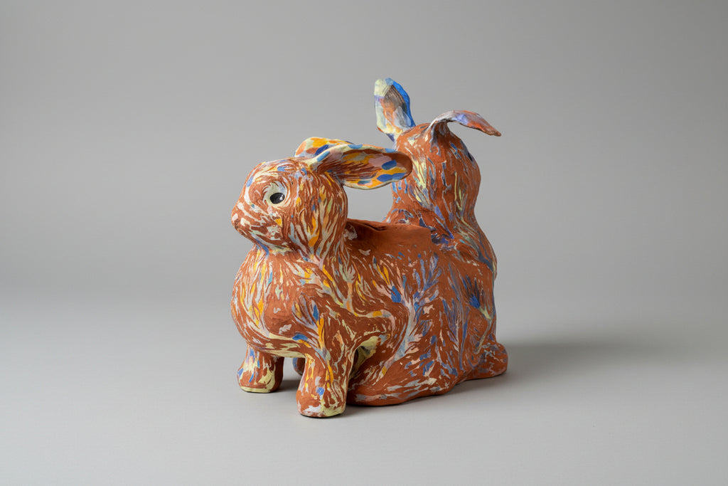 Ceramic rabbit-shaped planter with multicolored patterns on a wooden surface.