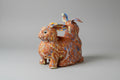 Ceramic rabbit-shaped planter with multicolored patterns on a wooden surface.