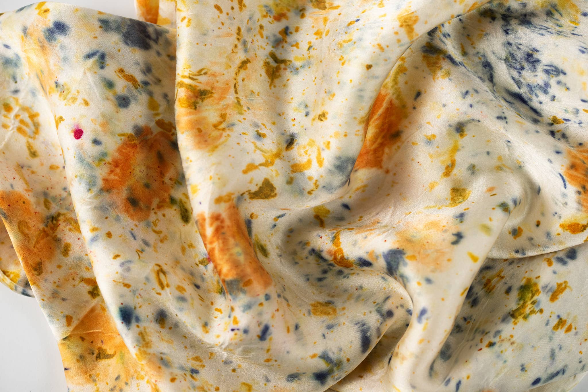 Close-up of a silk fabric with orange, blue, and yellow patterns.