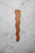 Wooden spatula with wavy design on a marble surface