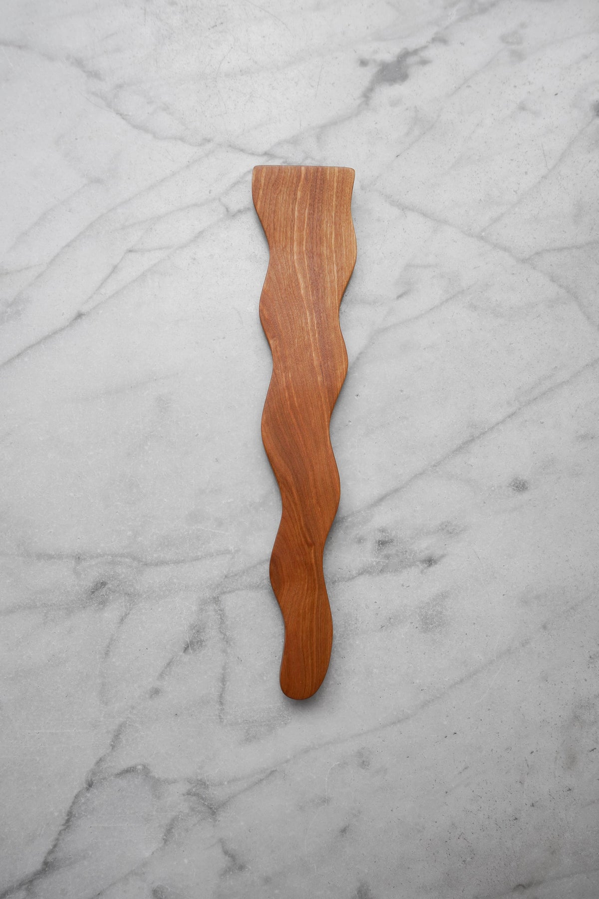 Wooden spatula with wavy design on a marble surface