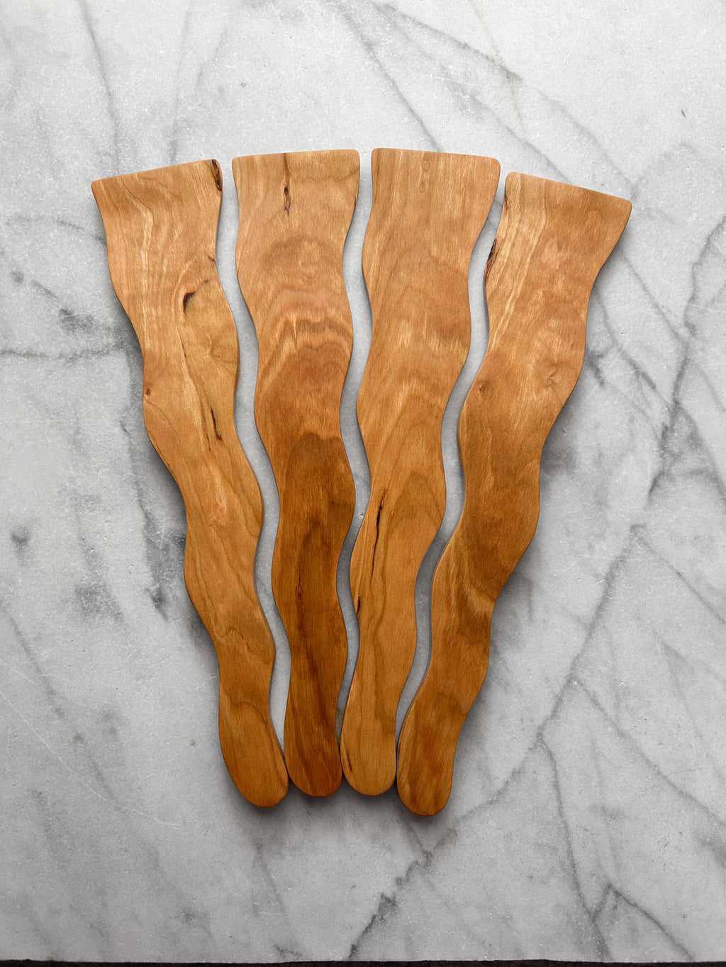 Wooden cutting board with wavy design on a marble surface