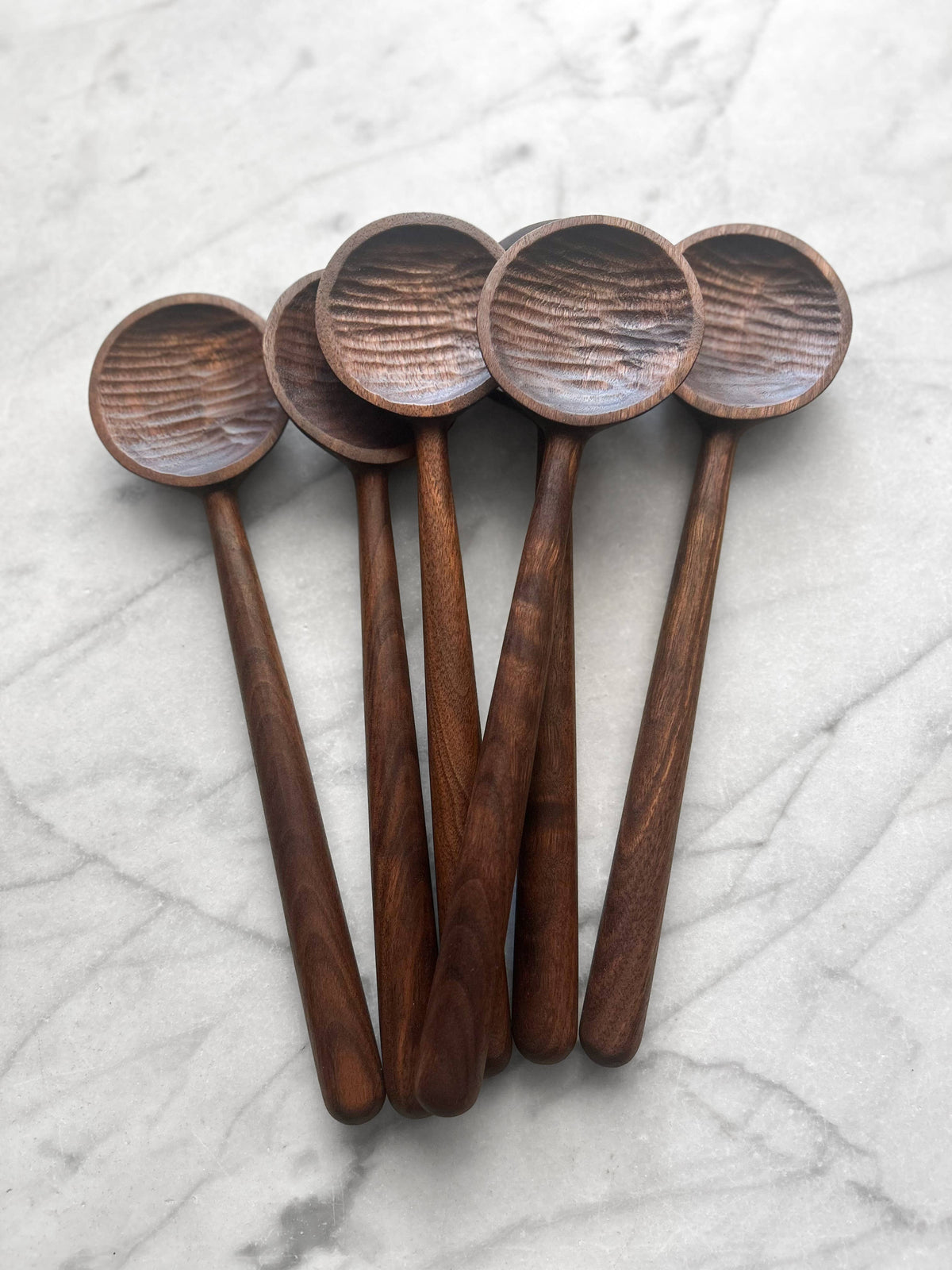 Set of five wooden spoons on a marble surface