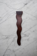 Wooden tool with a wavy design on a marble surface