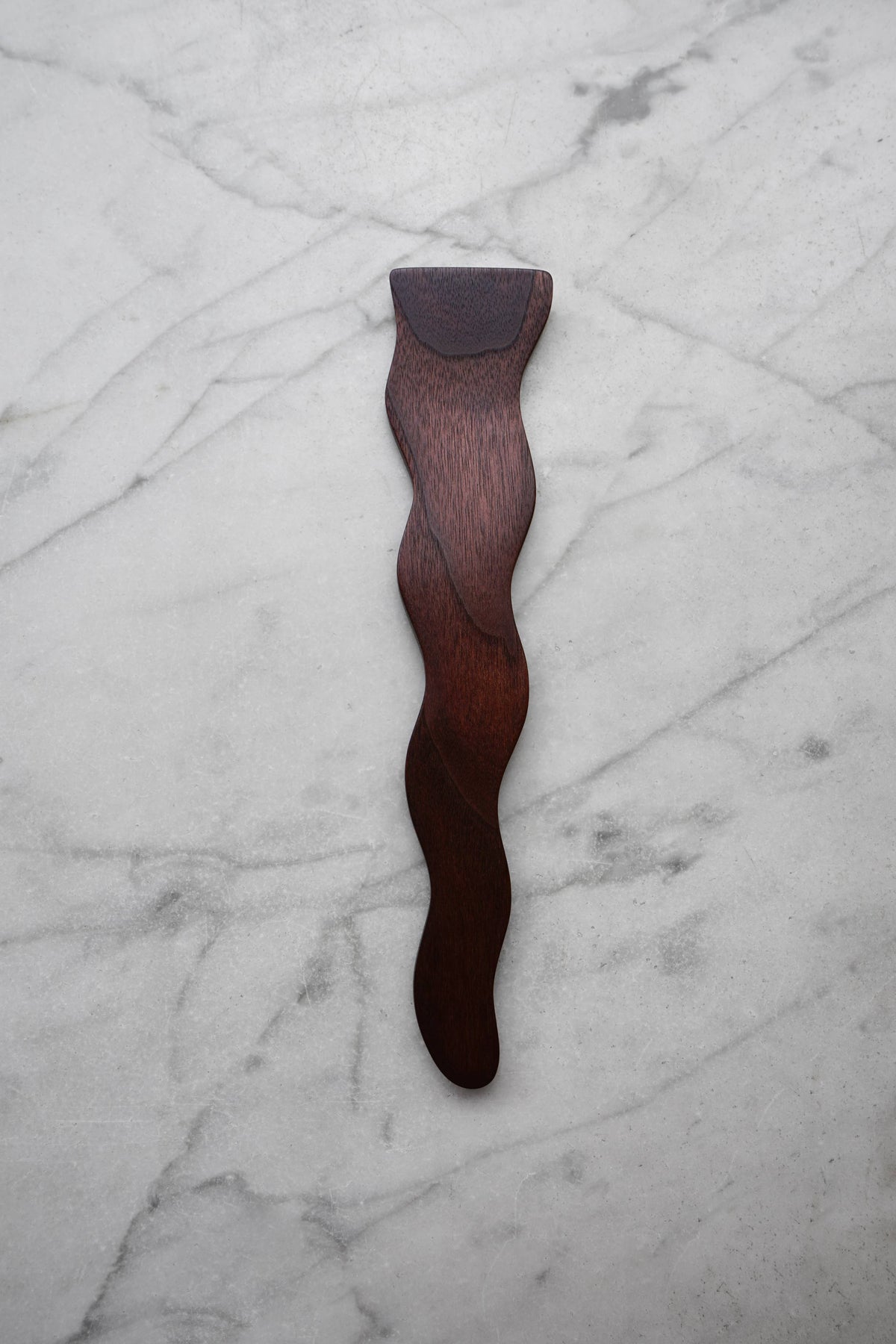 Wooden tool with a wavy design on a marble surface