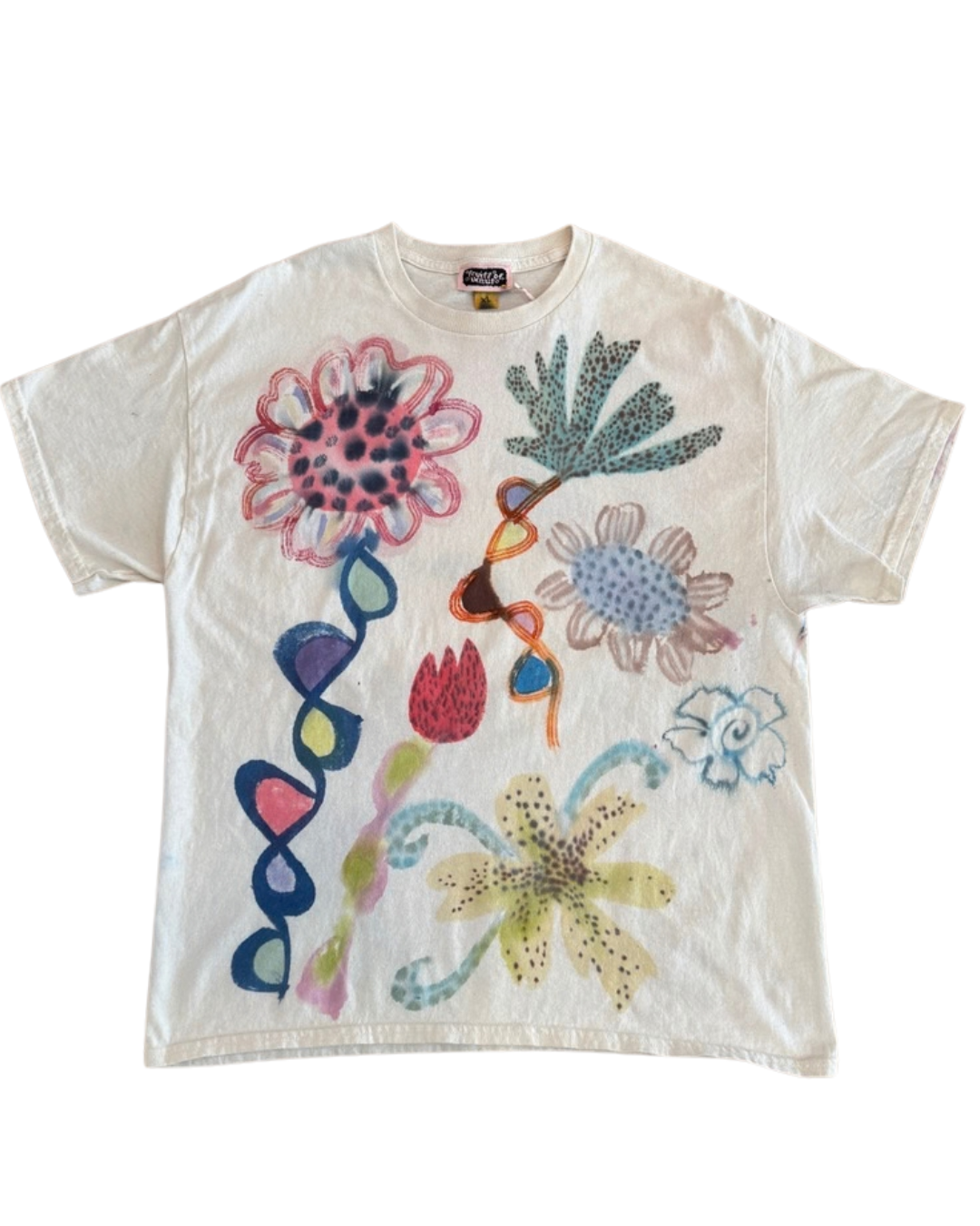 An off-white short-sleeve t-shirt featuring a colorful, hand-drawn style graphic print of various flowers and abstract organic shapes.