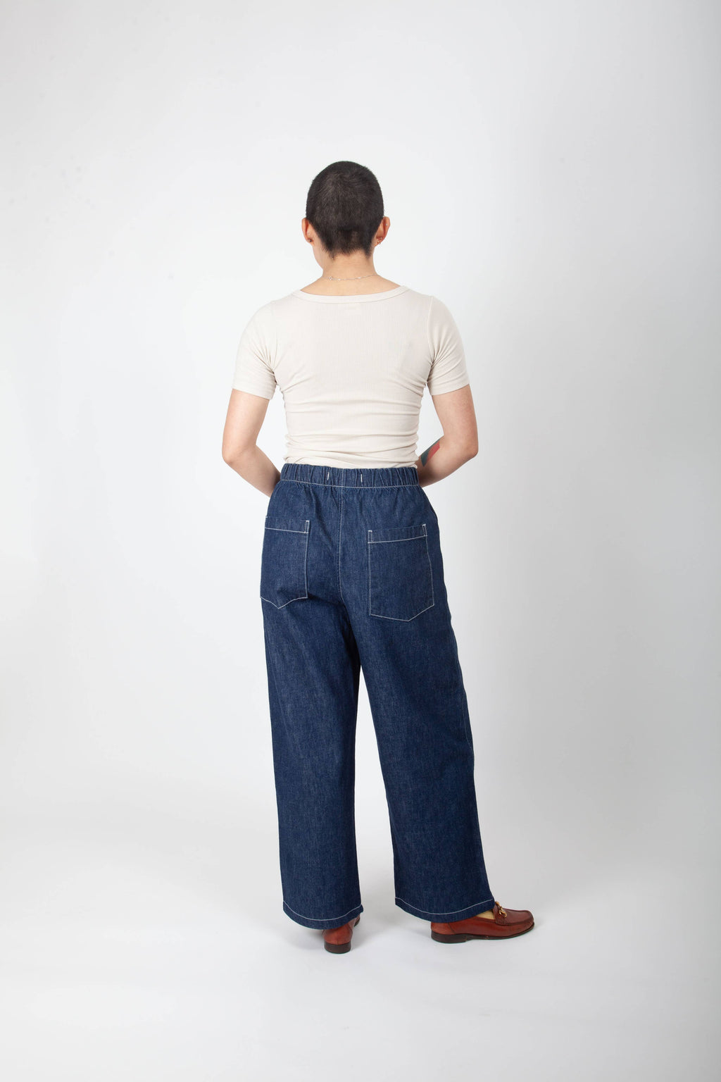 Person wearing blue jeans and a white top on a white background