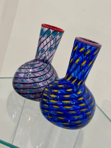 Two colorful glass vases on a clear surface