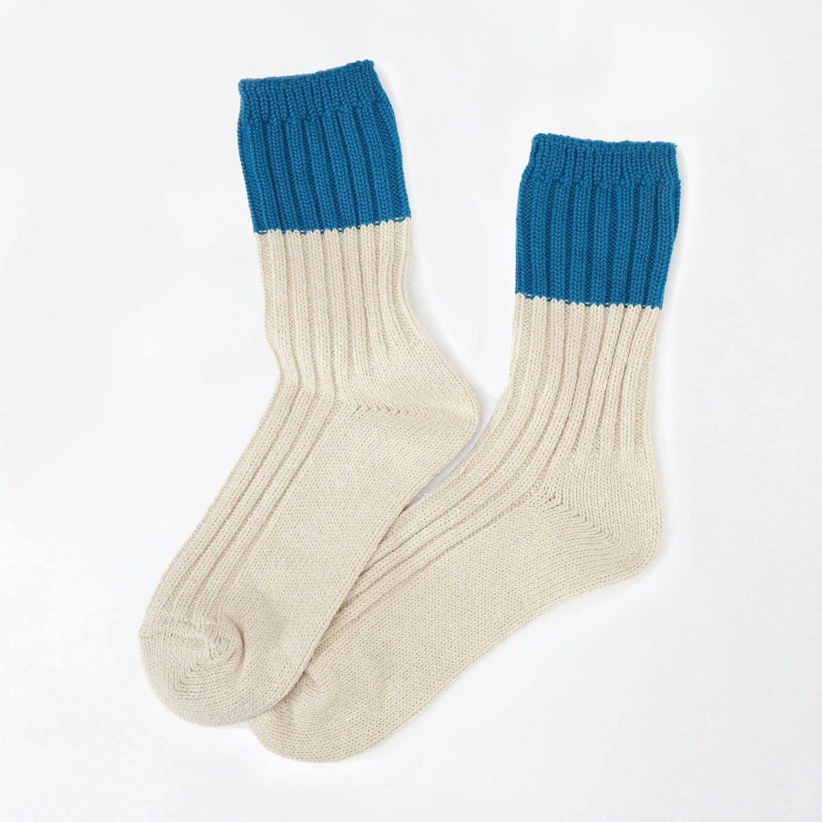 A pair of ribbed knit crew socks in cream and blue, arranged overlapping on a clean white background.