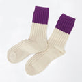 A pair of ribbed knit crew socks in cream with a contrasting purple cuff, displayed on a clean white background.