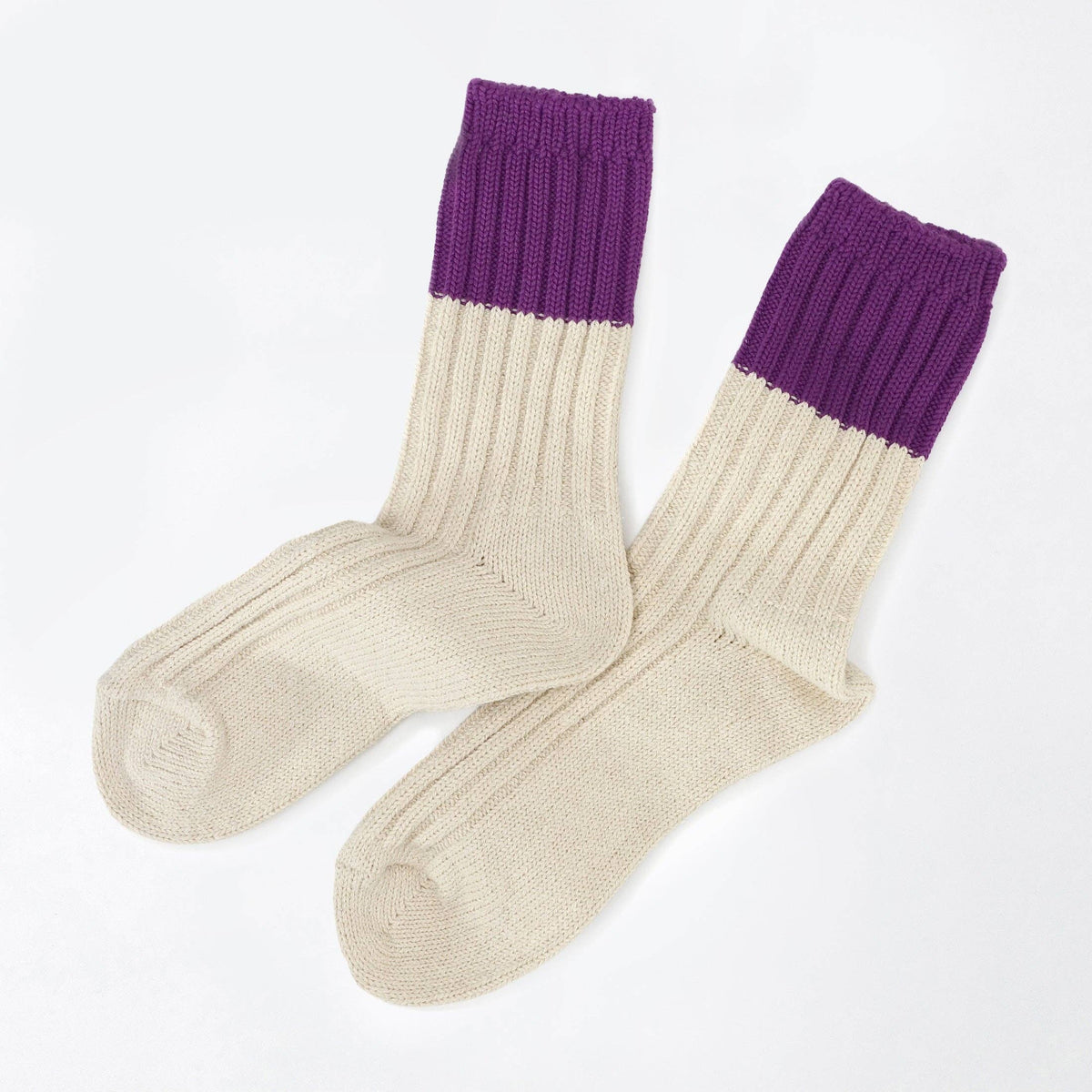 A pair of ribbed knit crew socks in cream with a contrasting purple cuff, displayed on a clean white background.