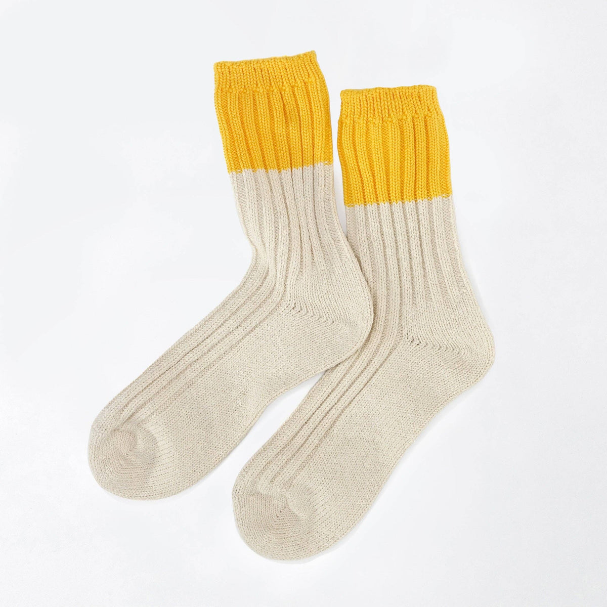 A pair of ribbed crew socks in cream and yellow, arranged overlapping on a clean white background.