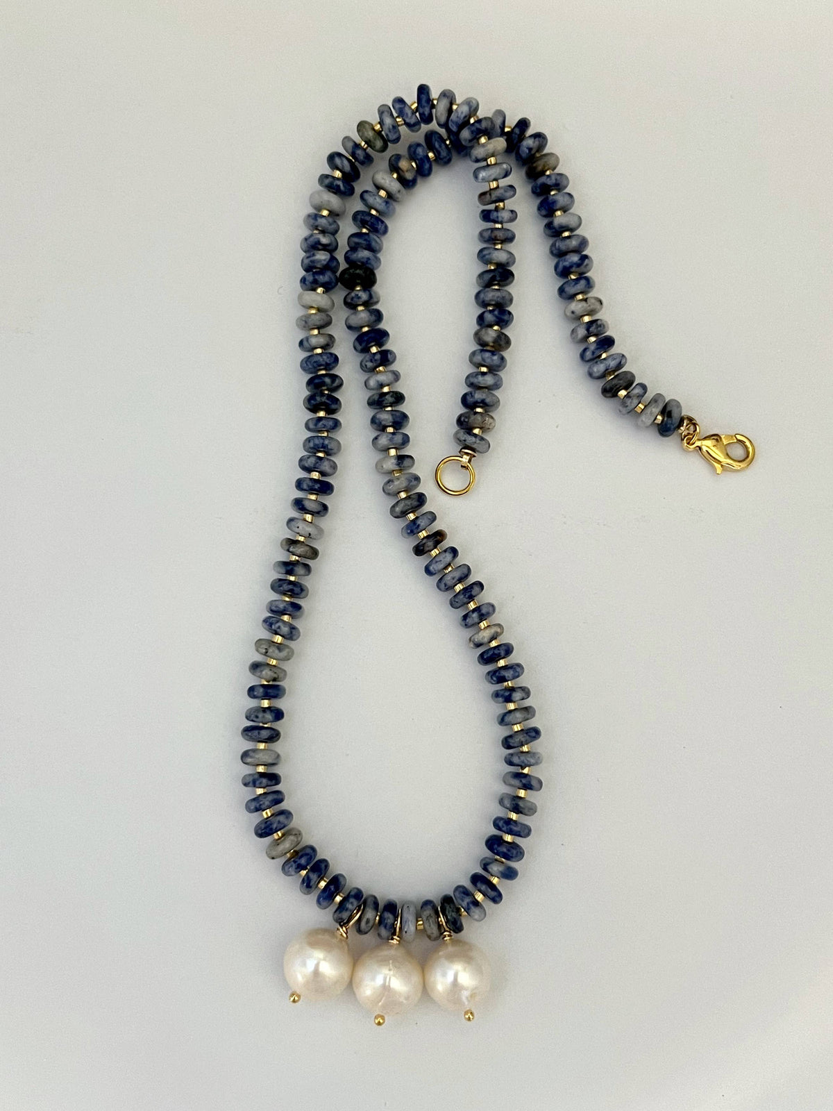 Necklace with blue and gray beads and white pearls on a light gray background