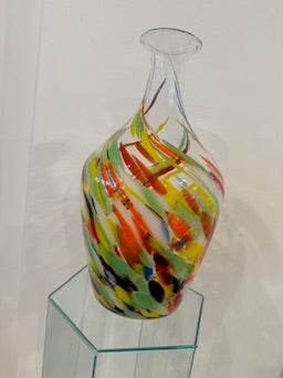 Colorful glass vase on a clear stand against a white background