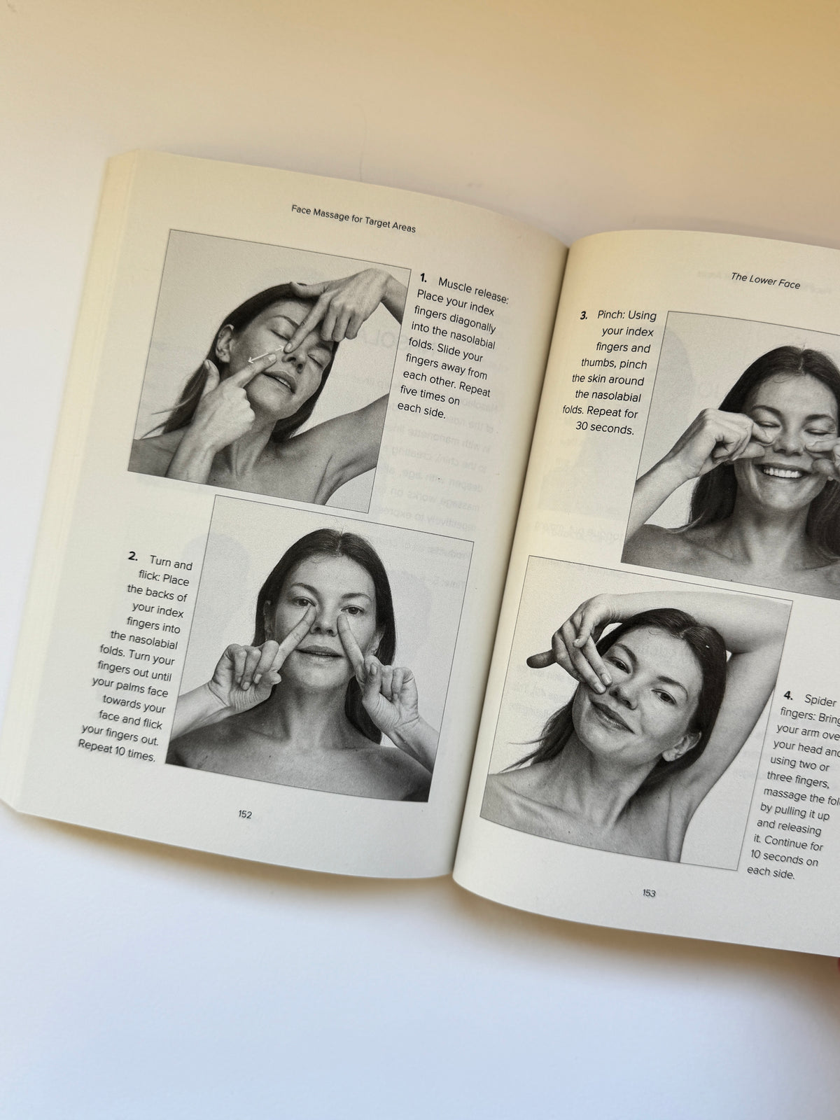 An open book showing two printed pages with black-and-white photos of a woman demonstrating facial massage or facial expression exercises, photographed on a light neutral background.