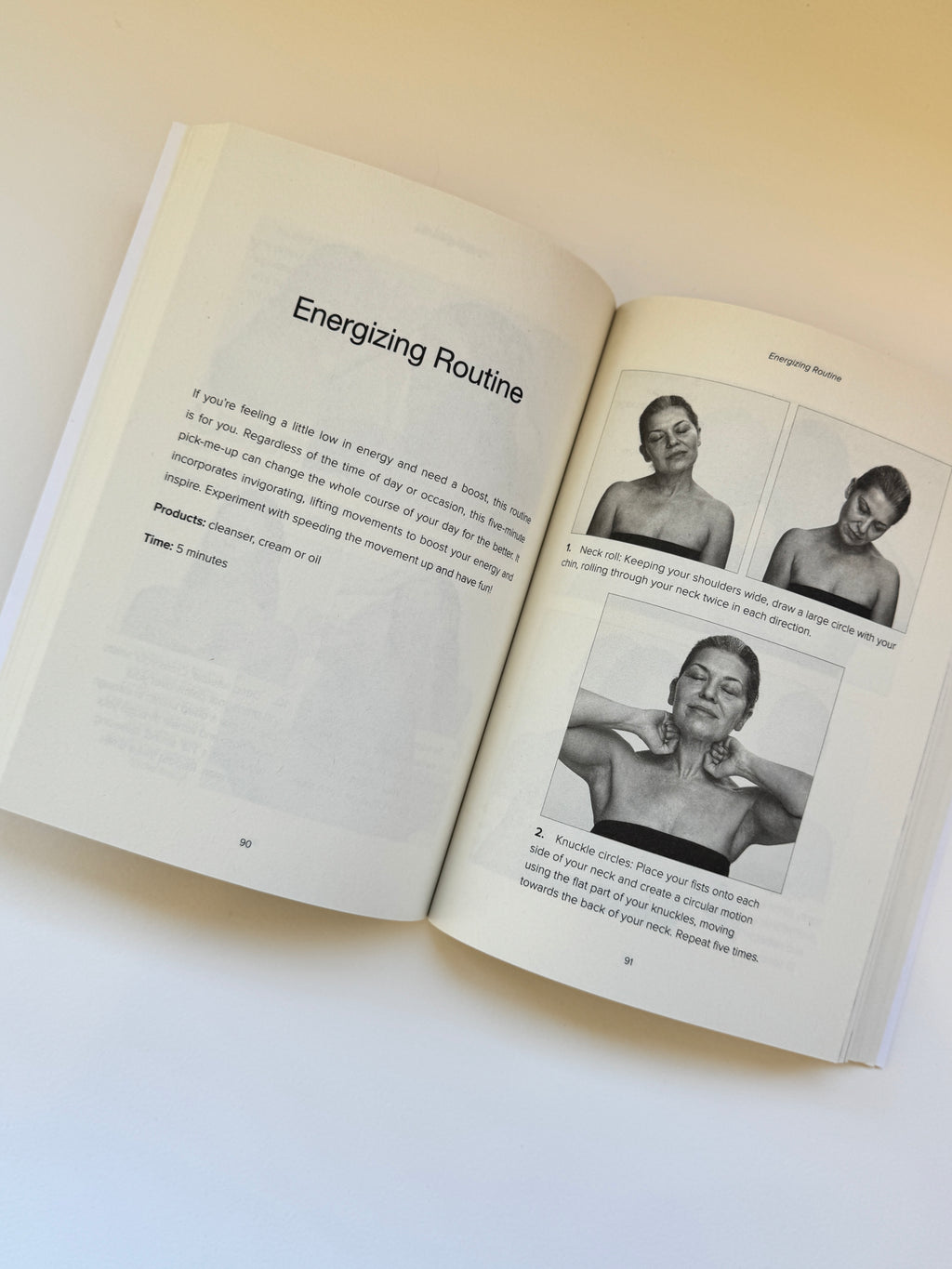 An open book showing pages titled 'Energizing Routine' with text and three black-and-white photos of a person's upper body, photographed on a light beige background.