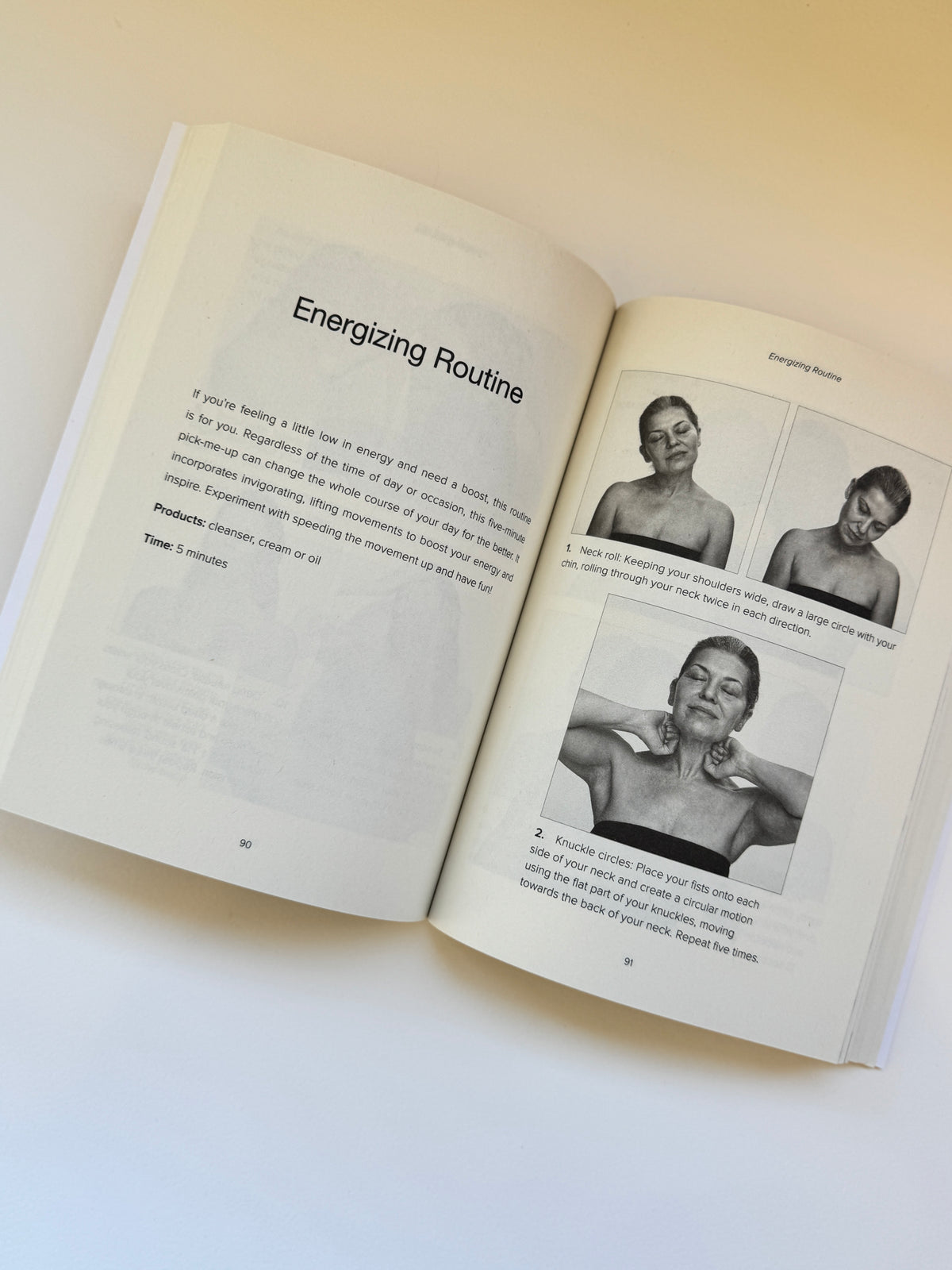 An open book showing pages titled 'Energizing Routine' with text and three black-and-white photos of a person's upper body, photographed on a light beige background.